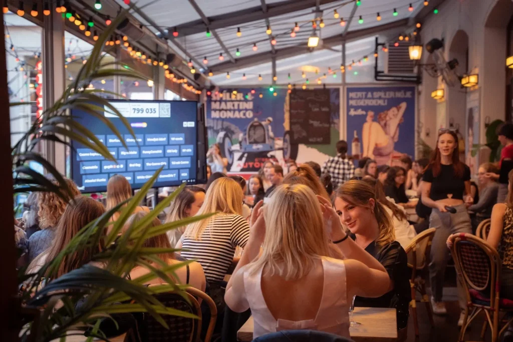 Év végi csapatépítő kvízest – Kahoot játék közben nevető kollégák, kvizestek.hu logóval